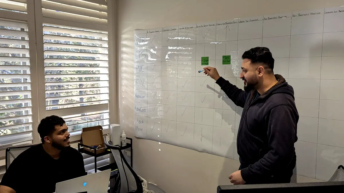 Two members of the KAI-2 team at a whiteboard, working through a project plan.